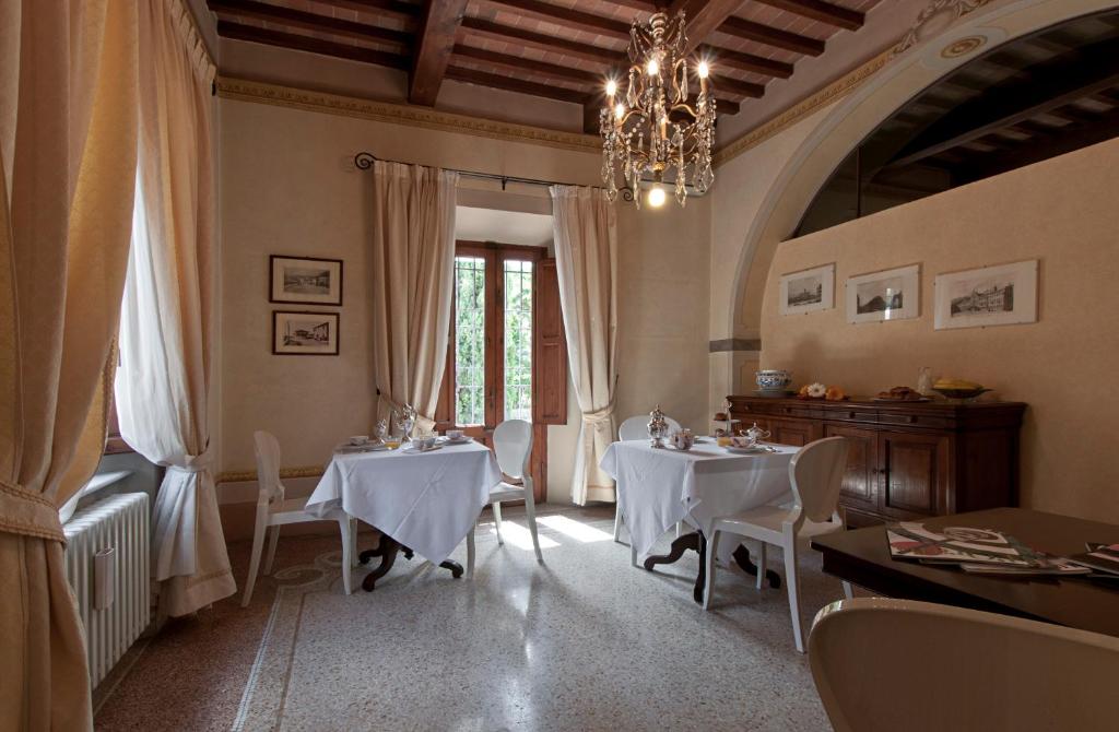 een eetkamer met 2 tafels en een kroonluchter bij VillAmorosa in Calci