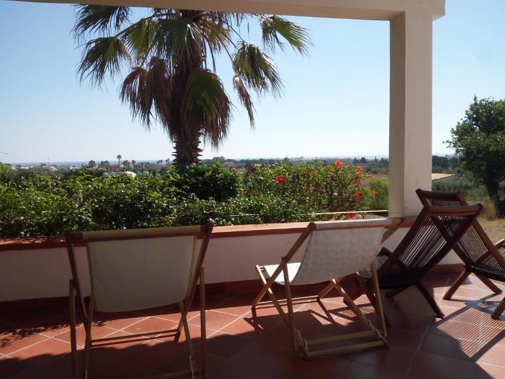 a porch with two chairs and a table and a palm tree at Marzamemi, campagna mare in Marzamemi