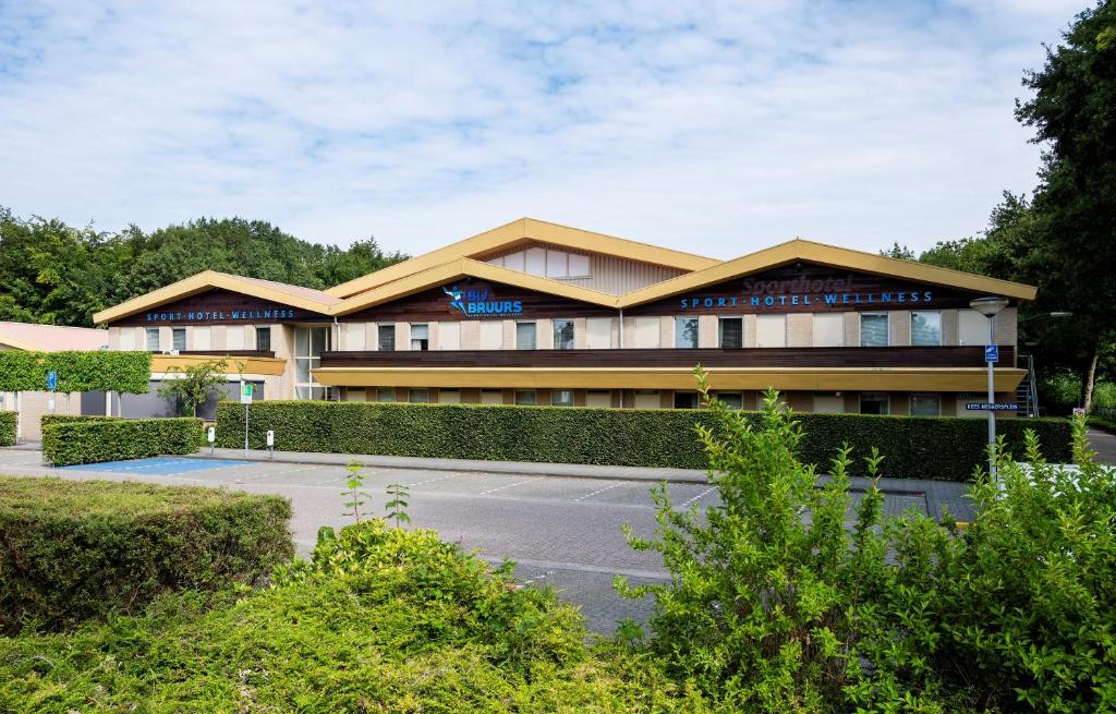 un bâtiment avec un parking en face de celui-ci dans l'établissement Sporthotel Bruurs, à Baarle-Nassau