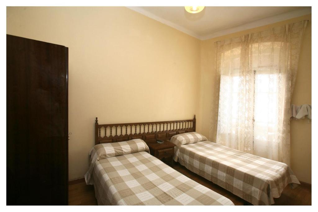 2 camas en una habitación con ventana en Hostal Galicia, en Ribadeo