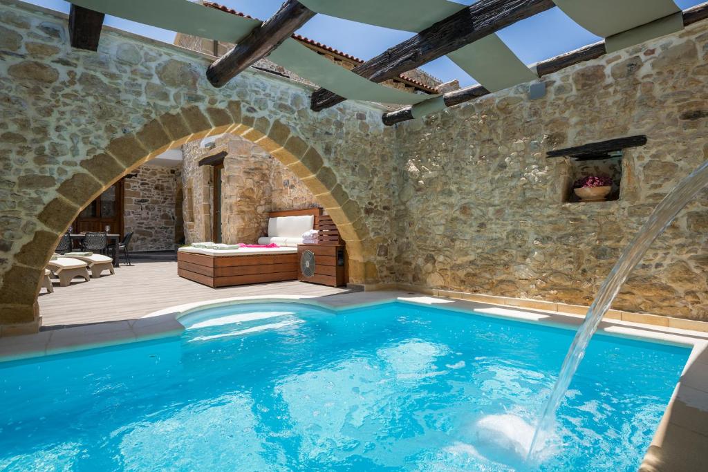 una piscina cubierta en una casa con una pared de piedra en Doro Villas, en Dhrapaniás