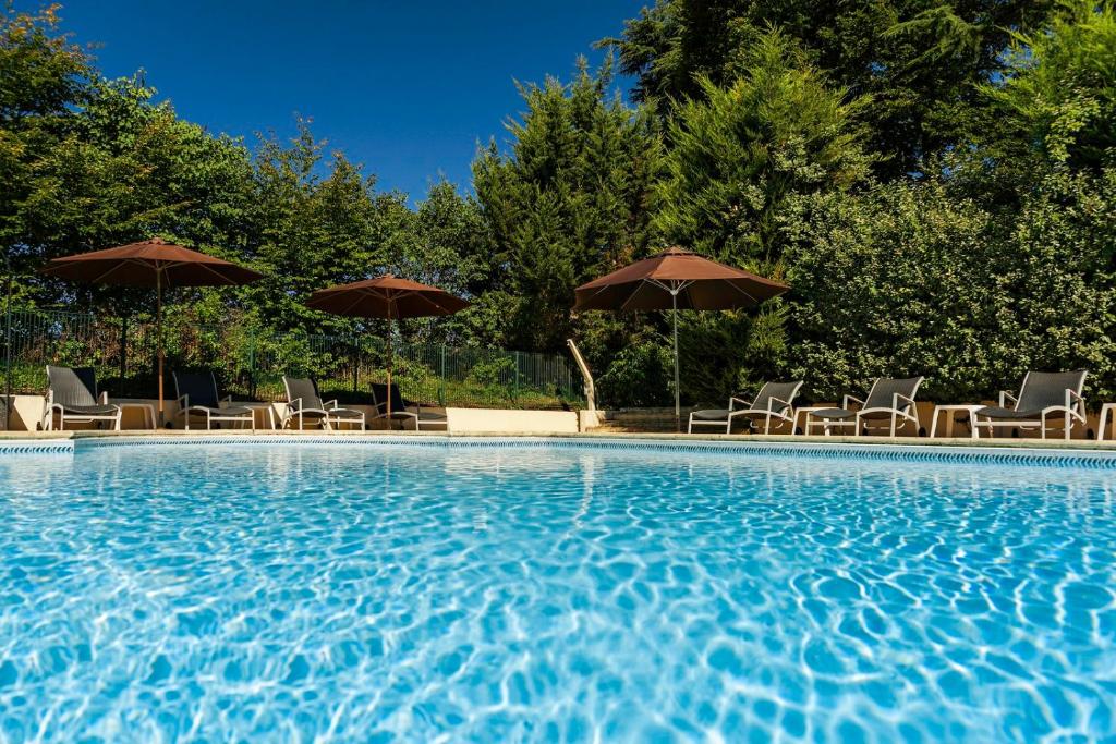 - une piscine avec des chaises longues et des parasols dans l'établissement Hôtel Restaurant du Château de la Tour, à Béguey