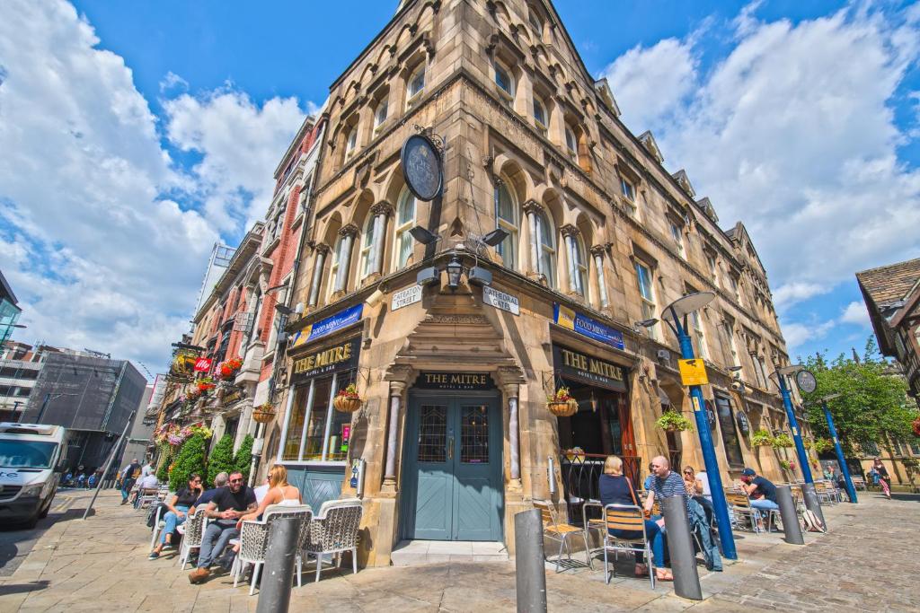 un grupo de personas sentadas fuera de un edificio en The Mitre Hotel, en Mánchester