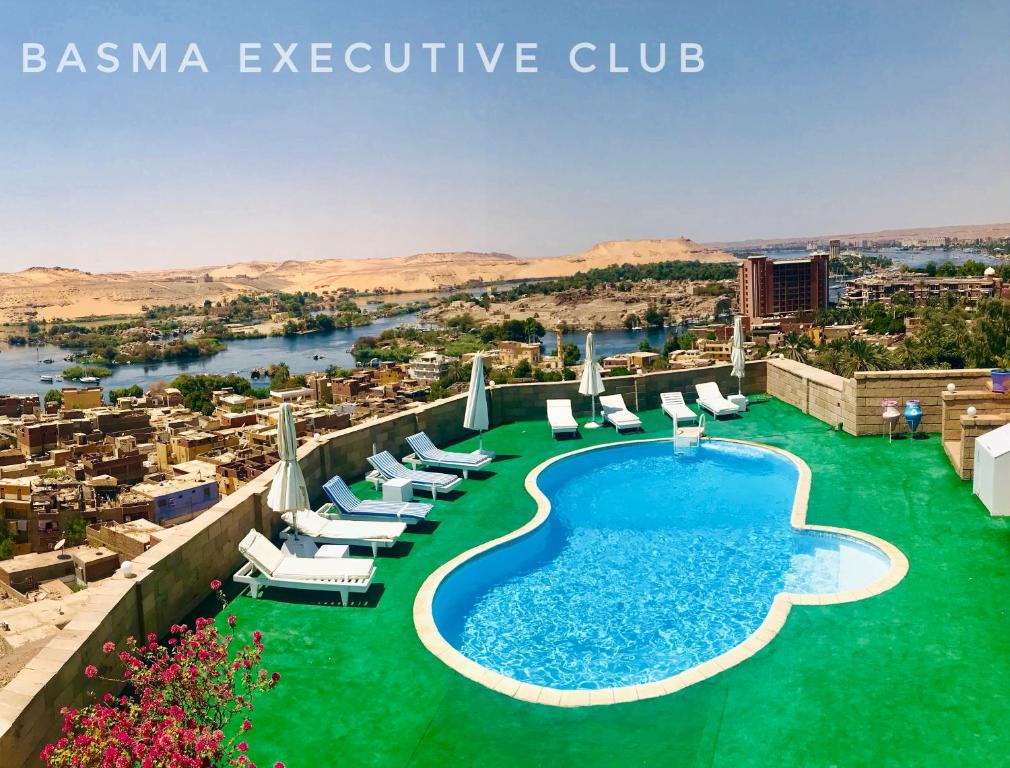 a resort with a pool and chairs and a city at Basma Club in Aswan