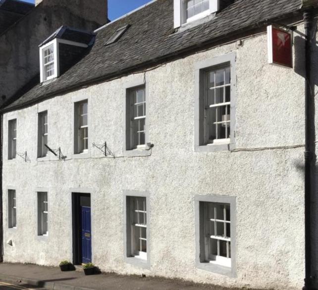 a white building with windows and a blue door at Springwells in Dunkeld