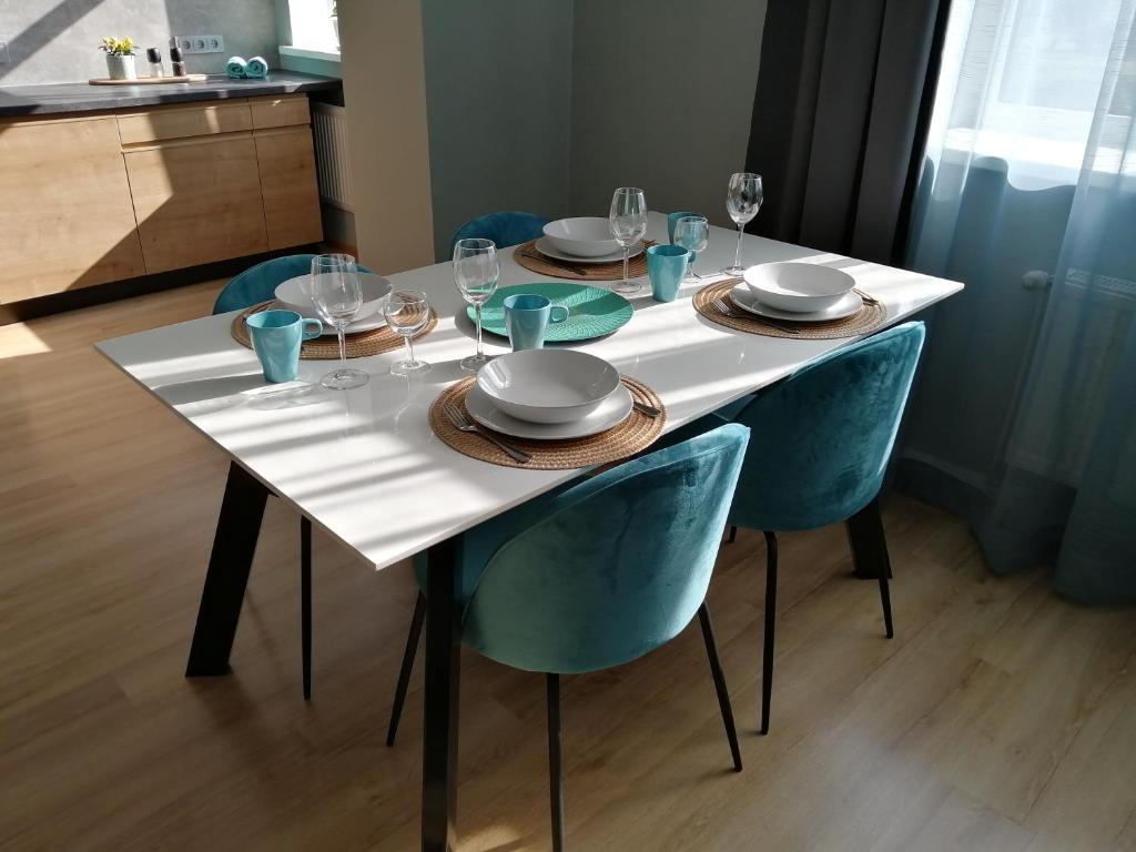 una mesa blanca con sillas, platos y copas de vino en Bauskas Street Apartments en Riga