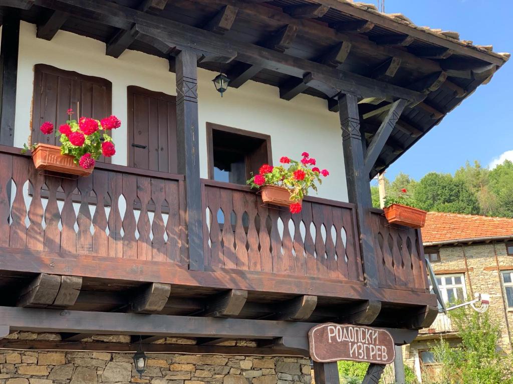 un balcón de madera con flores en un edificio en Къща за гости Родопски изгрев en Leshten
