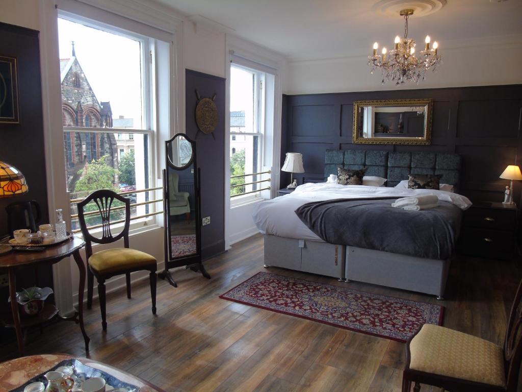 um quarto com uma cama grande, uma mesa e cadeiras em The Warren Belfast em Belfast