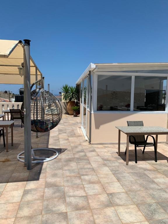 een patio met tafels en een parasol op een gebouw bij Pension Nikos in Pitsidia