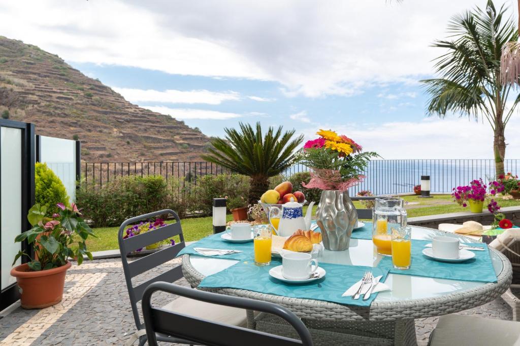 een tafel met fruit en sap op een patio bij Zeza´s Garden in Calheta