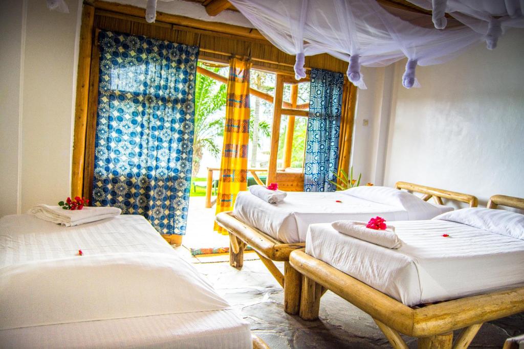a room with three beds and a window at Paradis Malahide in Gisenyi