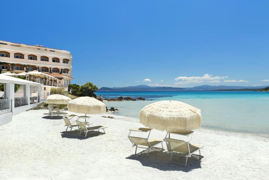 a beach with chairs and umbrellas overlooking the ocean at Gabbiano Azzurro Hotel & Suites in Golfo Aranci
