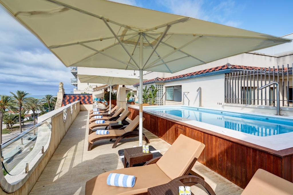a patio with a pool and chairs and an umbrella at Sercotel Kalma Sitges in Sitges