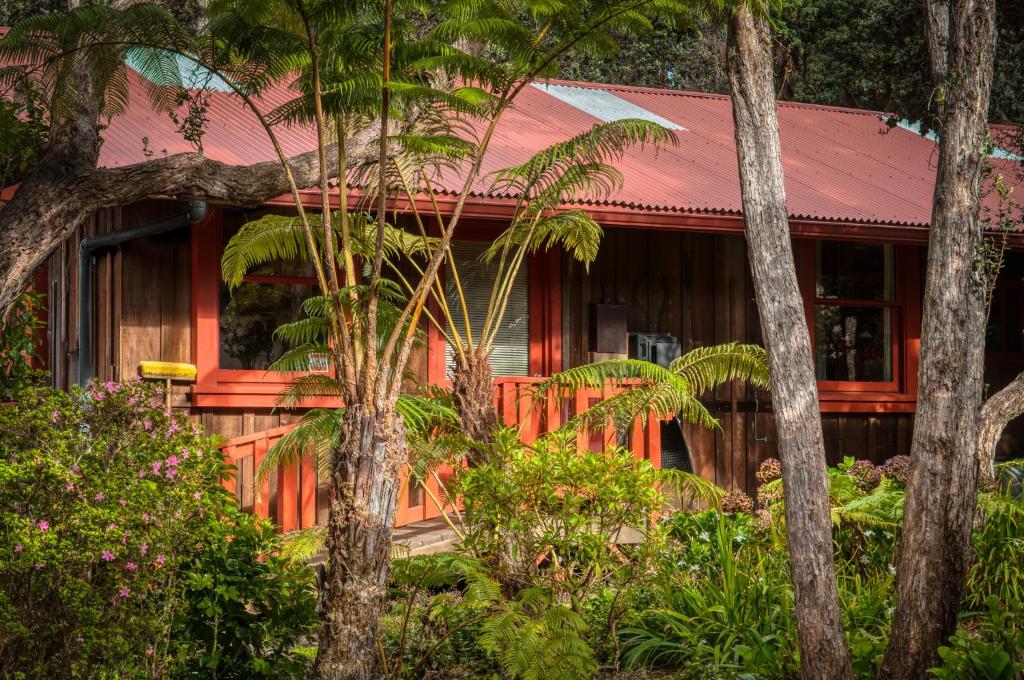 una casa rossa nel bosco con alberi di Crater Rim Cabin a Volcano