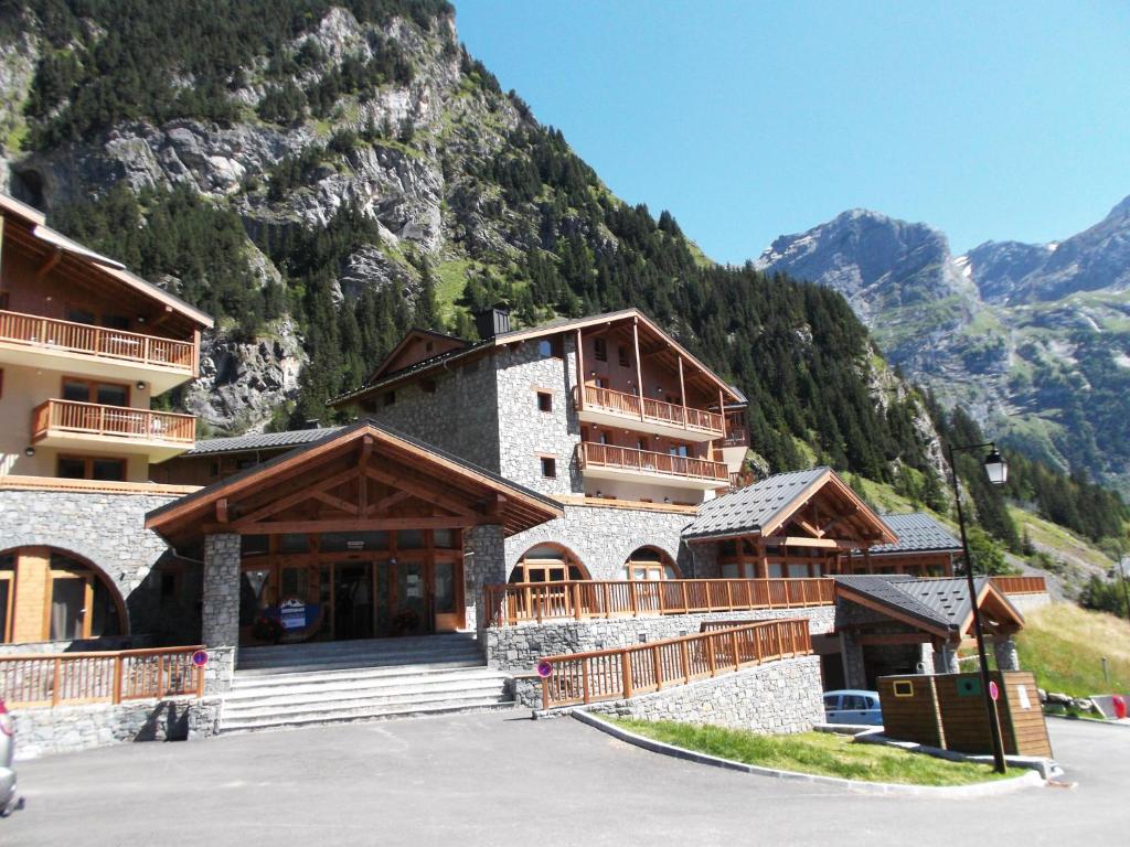 un grand bâtiment avec des montagnes en arrière-plan dans l'établissement Lagrange Vacances Les Hauts de la Vanoise, à Pralognan-la-Vanoise