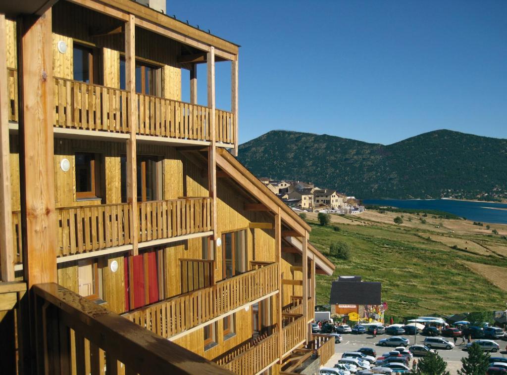 a building with cars parked in a parking lot at Lagrange Vacances L'Orée des Cîmes in Les Angles