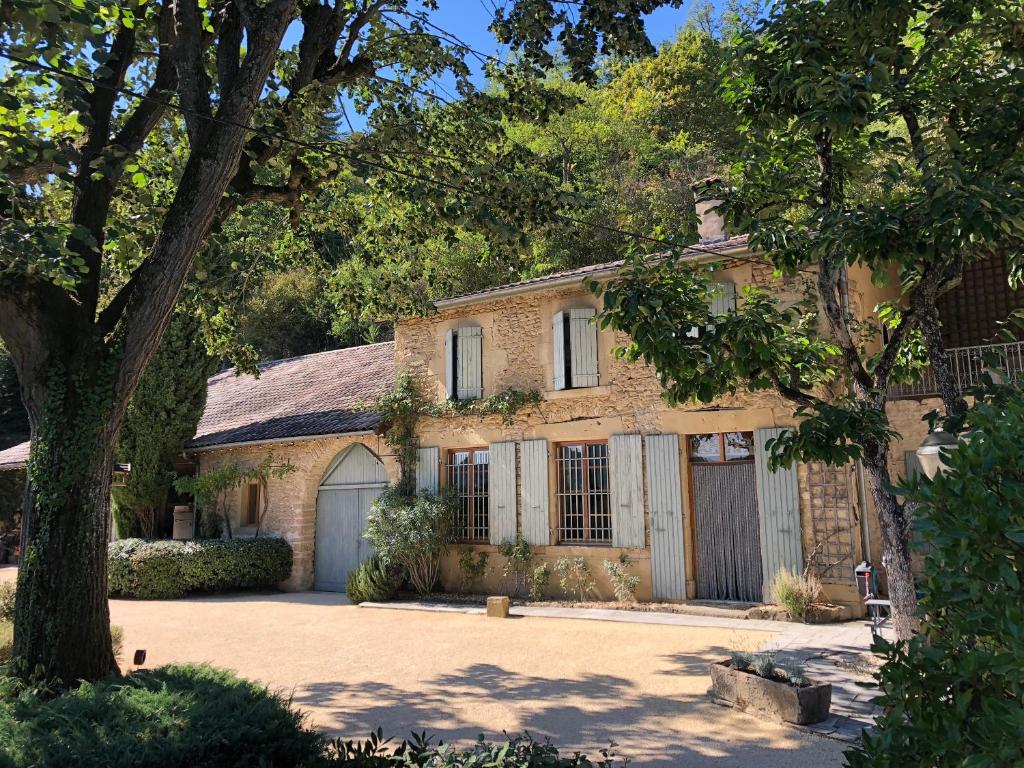 ein Steinhaus mit einer Garage und einem Baum in der Unterkunft Mas des Poutres - Gîte Rose in Charmes-sur-lʼHerbasse