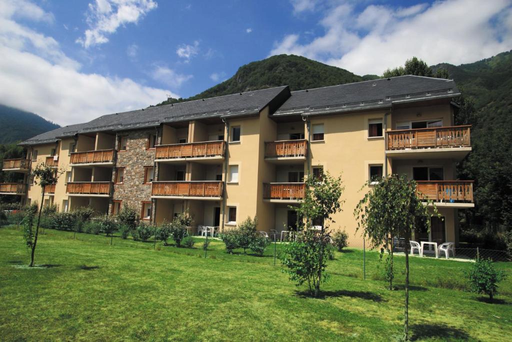 ein Apartmenthaus mit Rasen davor in der Unterkunft Lagrange Vacances Les Pics d'Aran in Luchon