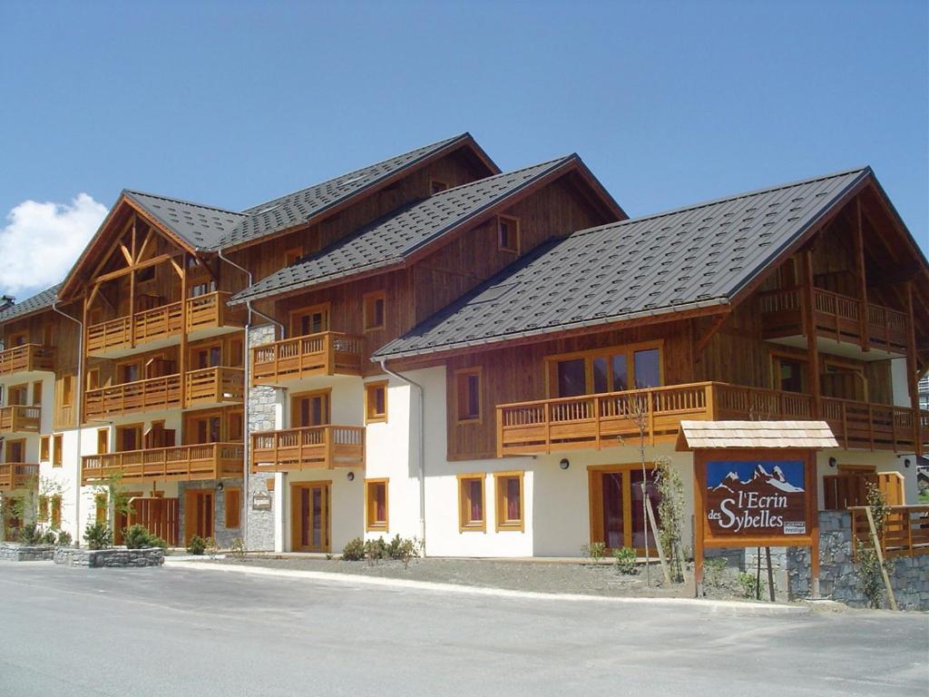 ein großes Holzgebäude mit einem Schild davor in der Unterkunft Lagrange Vacances L'Ecrin des Sybelles in La Toussuire