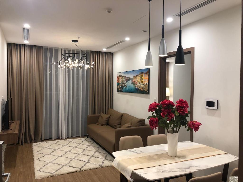 a living room with a couch and a table with flowers at Luxury Condotel 2BR Vinhomes Skylake Keangnam - Netflix free in Hanoi