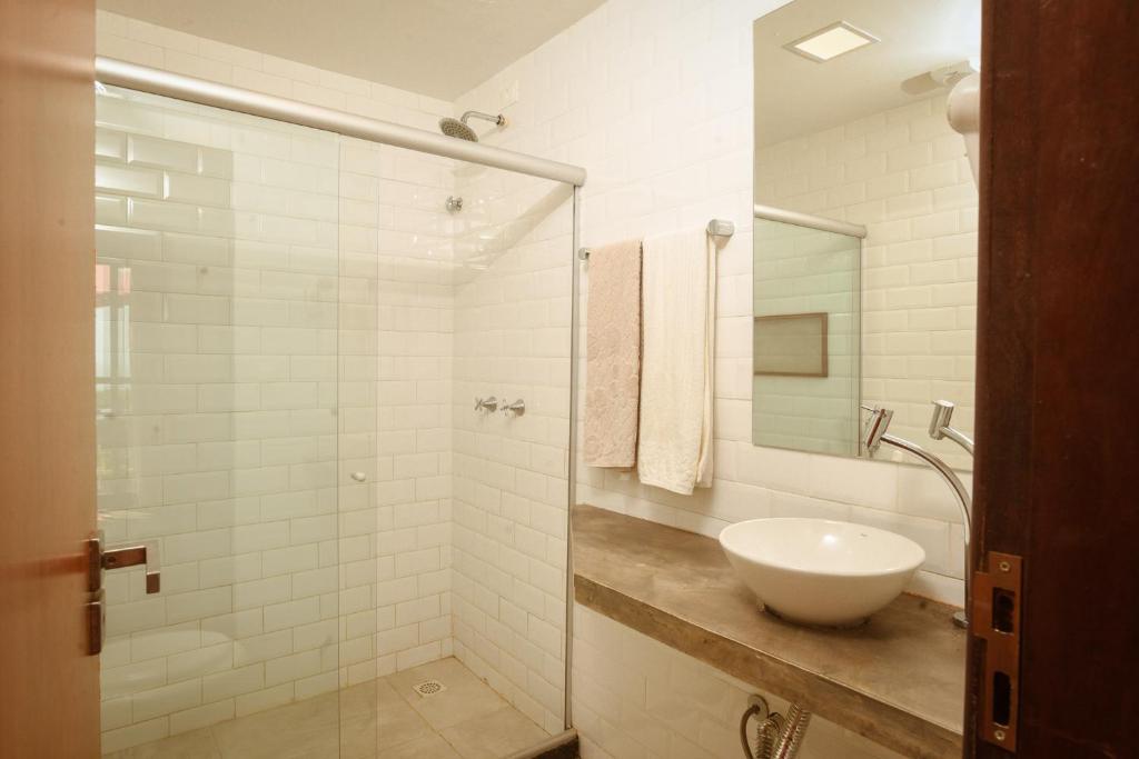 uma casa de banho branca com um lavatório e um chuveiro em Alto Mar Guest House em Fernando de Noronha