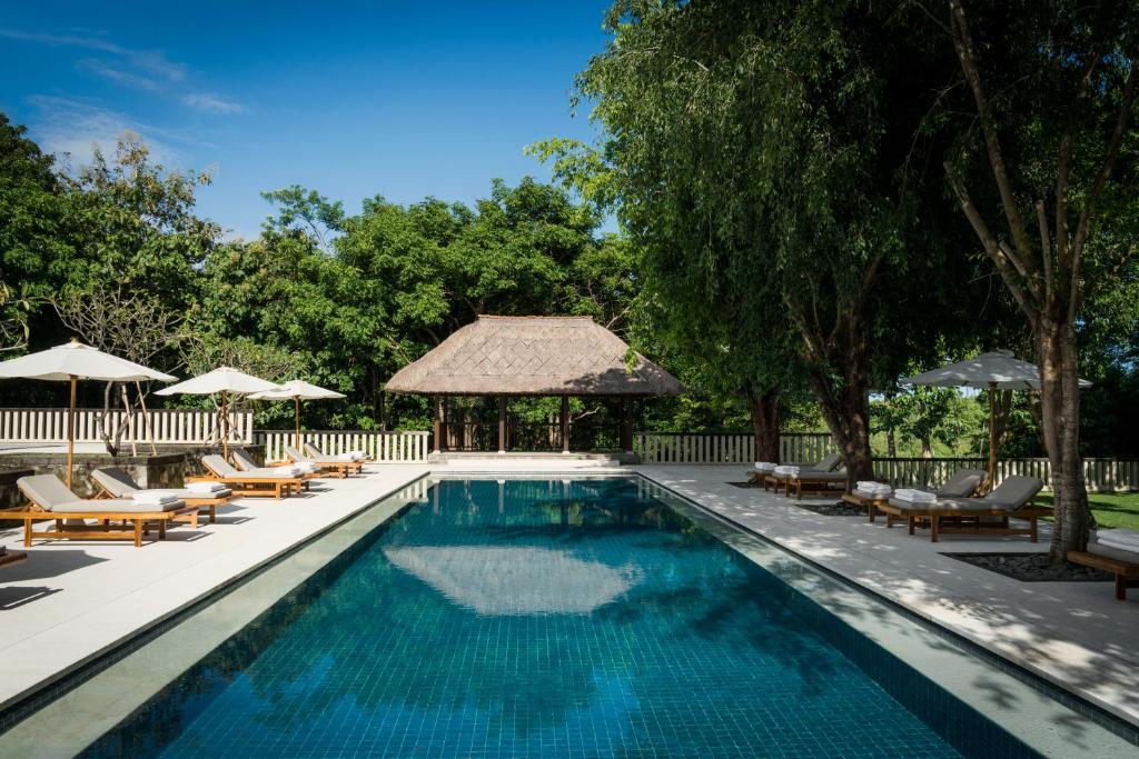 - une piscine avec des chaises longues et un kiosque dans l'établissement REVĪVŌ Wellness Resort Nusa Dua Bali, à Nusa Dua