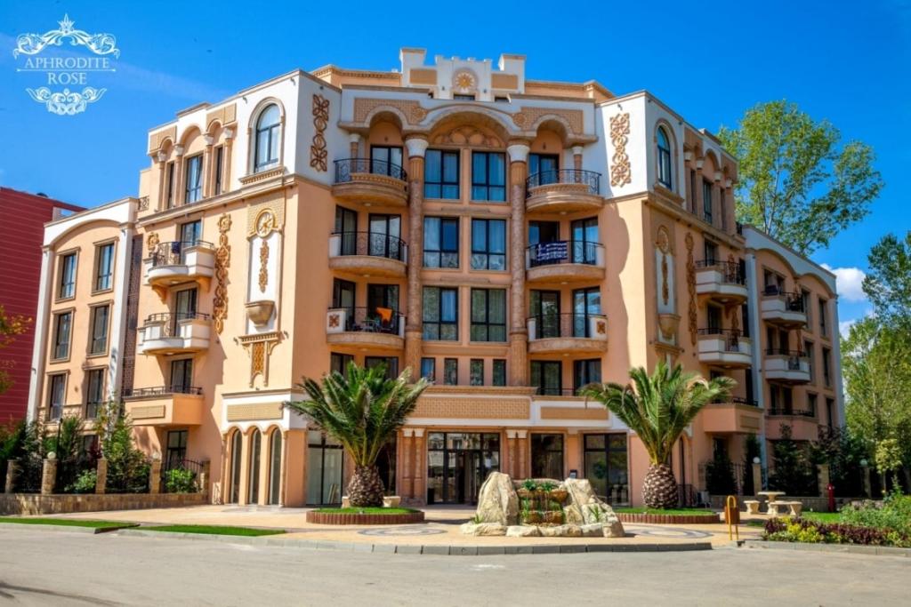 a large building with palm trees in front of it at Апартаменты Aphrodite Roce in Sunny Beach