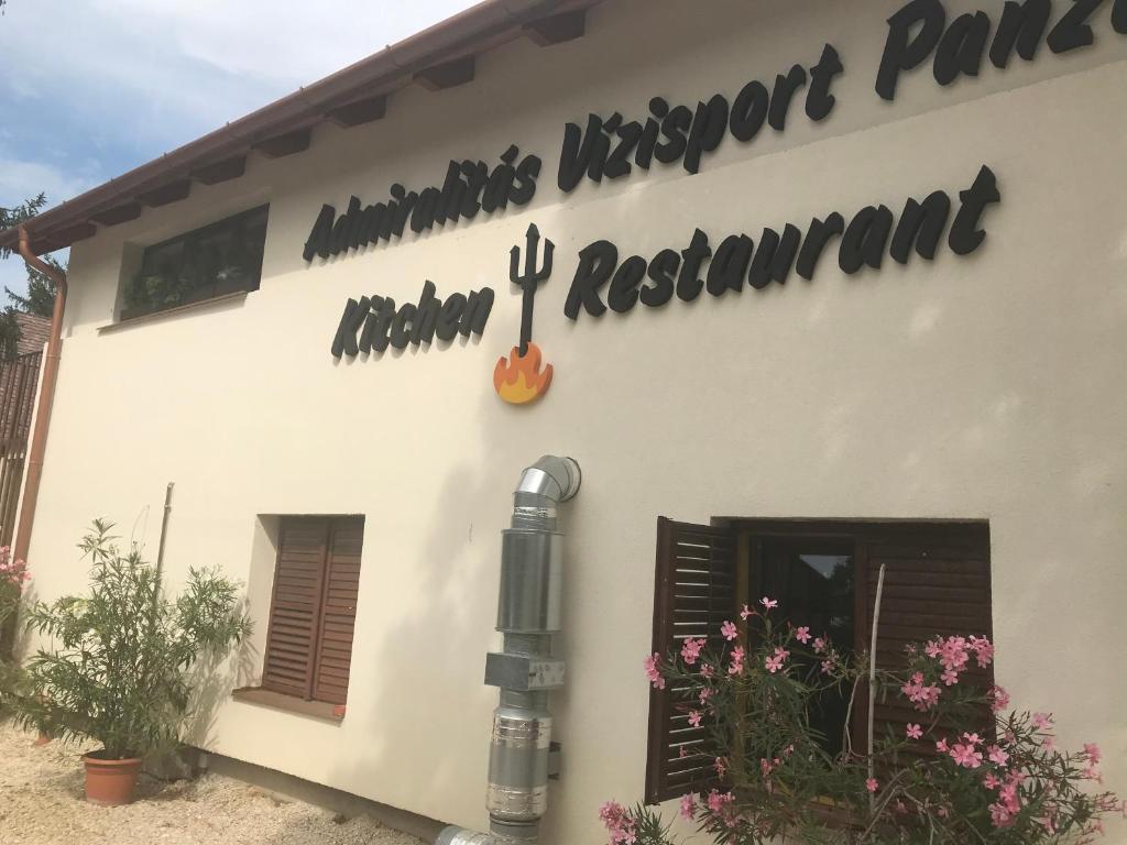 un edificio blanco con un cartel en el costado en Admiralitás Kitchen and Restaurant, en Leányfalu