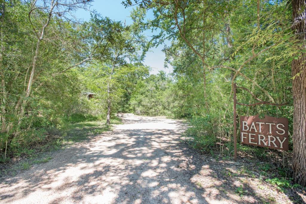 a dirt road through a forest with a sign that reads bats ferry at 7F Lodge and Events in College Station