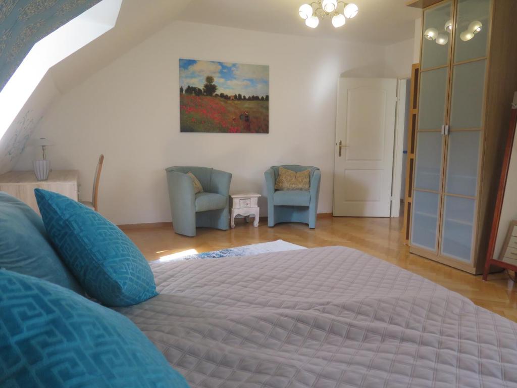 a bedroom with a large bed and two chairs at Schoenbrunn Gardens Deluxe Apartment in Vienna