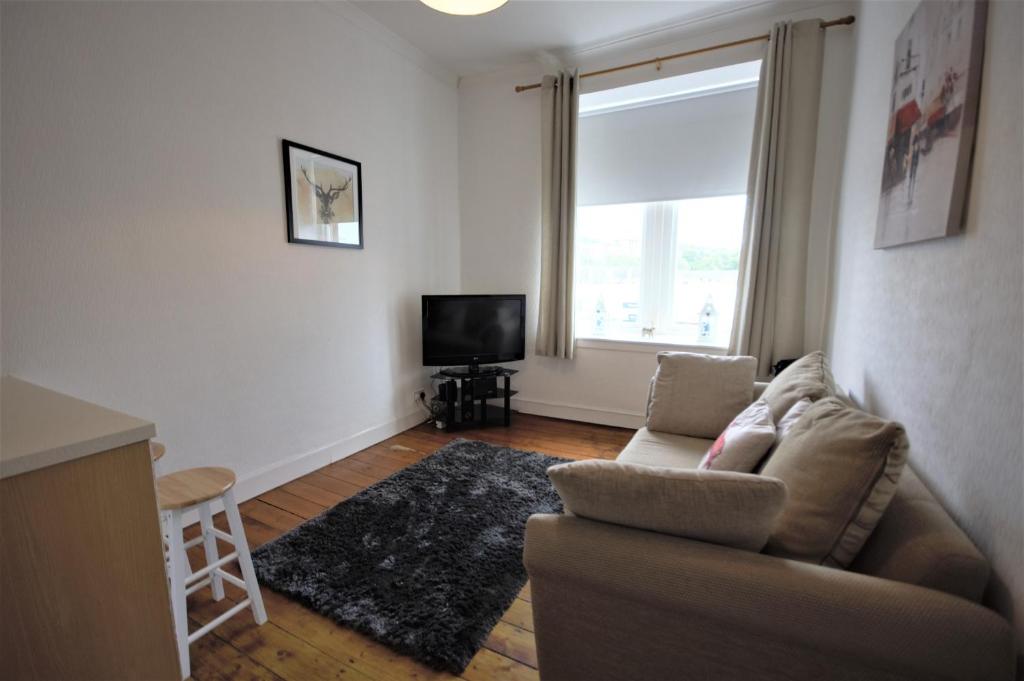 a living room with a couch and a television at Bright and Cosy West End Apartment in Glasgow