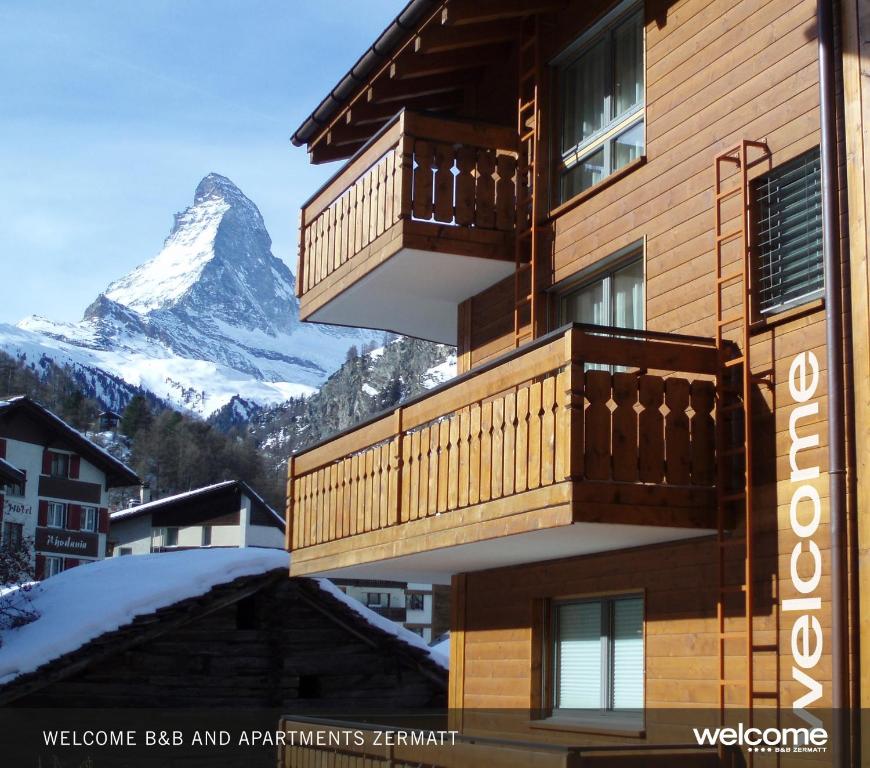 un edificio con un balcón con una montaña en el fondo en Haus Welcome, en Zermatt