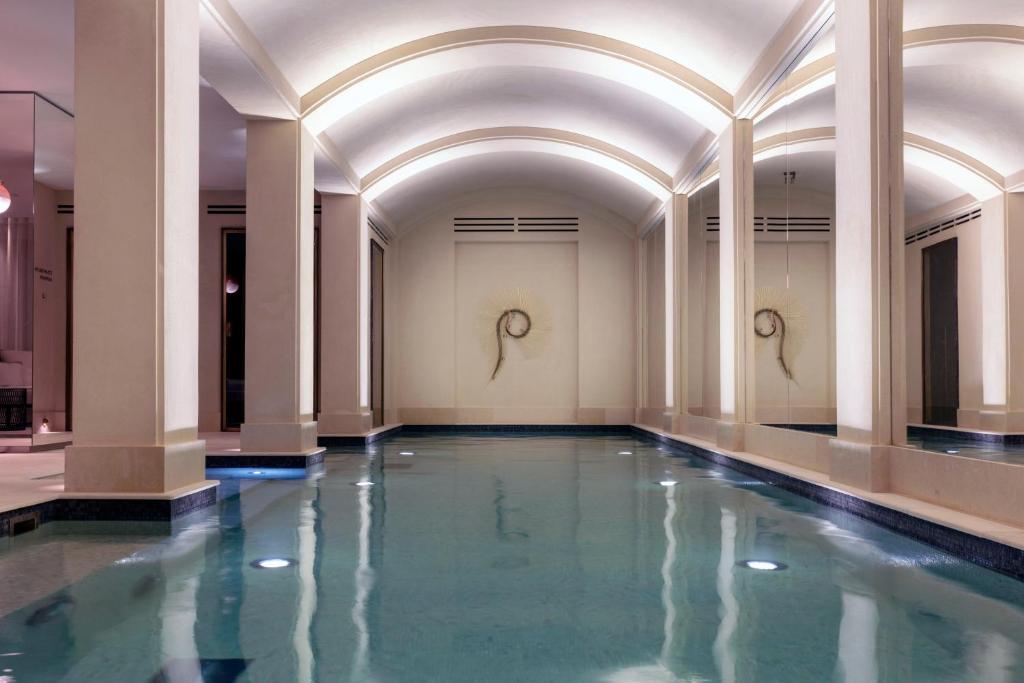 a swimming pool in a building with columns and water at Les Jardins du Faubourg Hotel & Spa by Shiseido in Paris