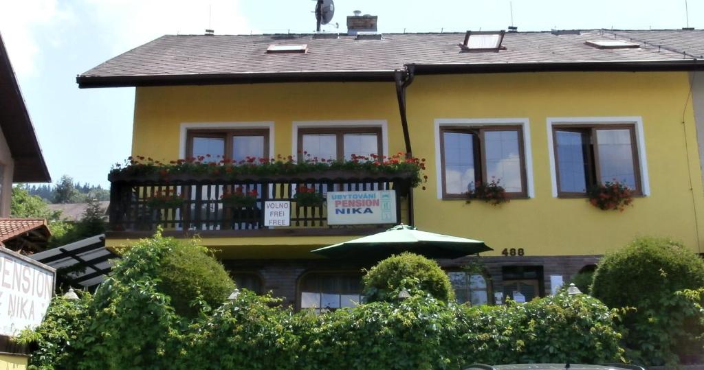 ein gelbes Haus mit einem Balkon mit Blumen darauf in der Unterkunft Pension Nika in Český Krumlov