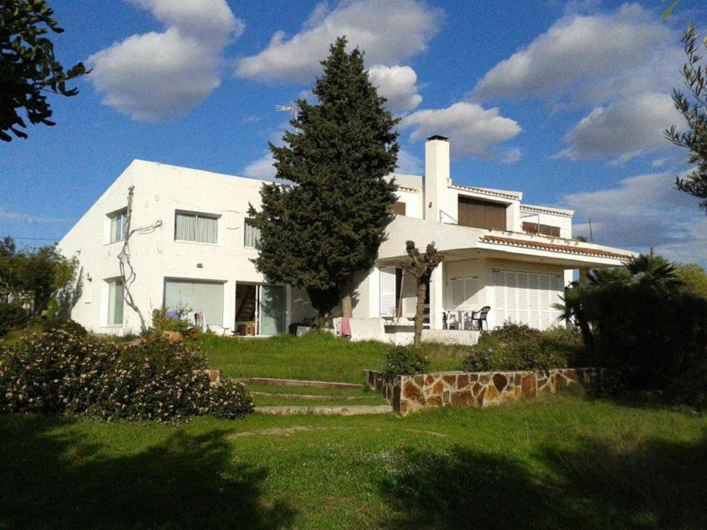 une maison blanche avec un arbre en face dans l'établissement Casa de la Playa en Torredembarra, à Creixell