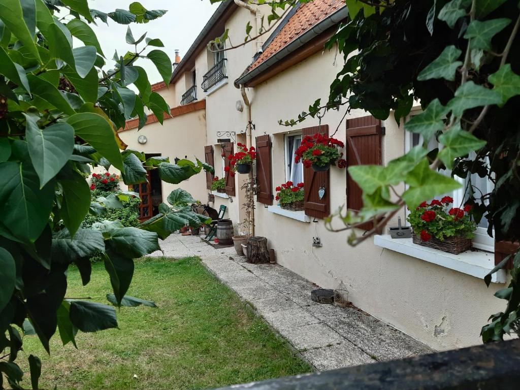 a courtyard of a house with flowers on the windows at Les Alouettes B&B in Hardecourt-aux-Bois