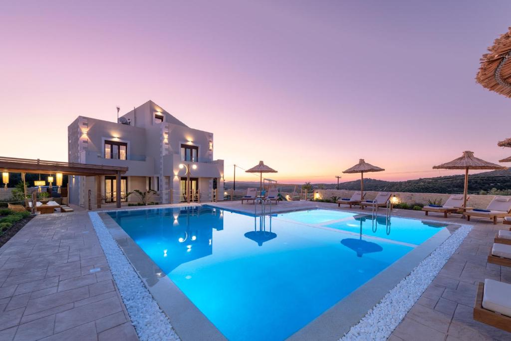 a villa with a swimming pool at sunset at Ivoni Villa, an Iconic Summer Retreat, By ThinkVilla in Perama