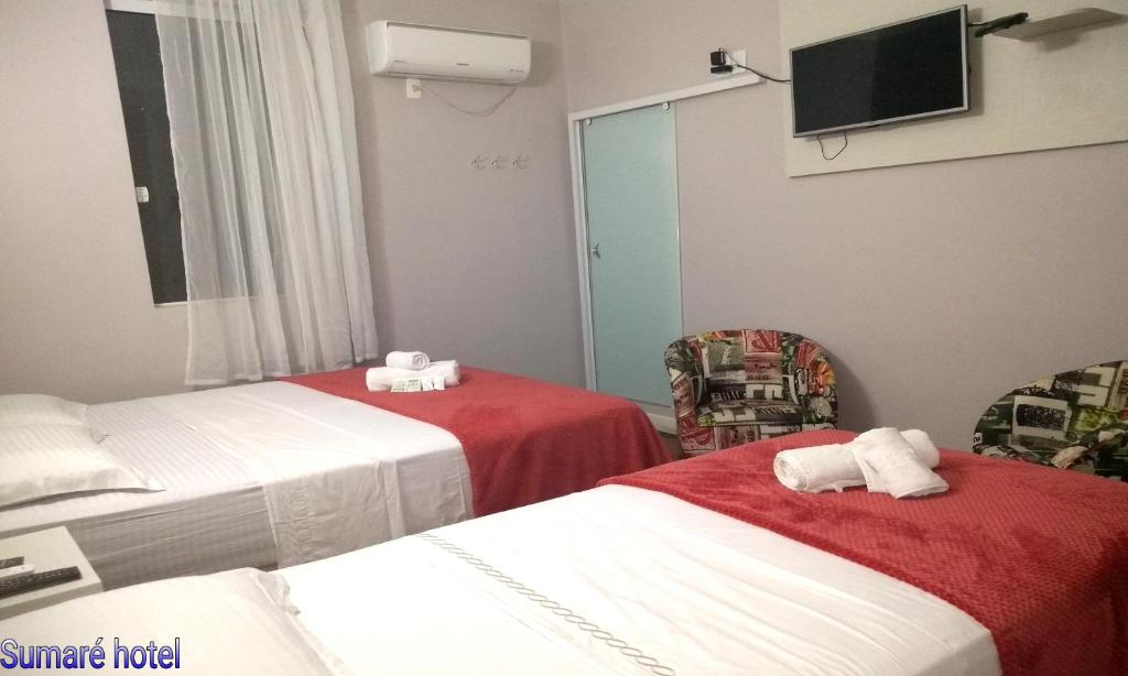 a hotel room with two beds and a television at Sumare Hotel in Florianópolis