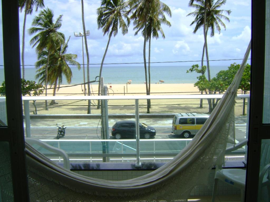 a hammock in a room with a view of the beach at Apartamento Cabo Branco Beira-Mar in João Pessoa