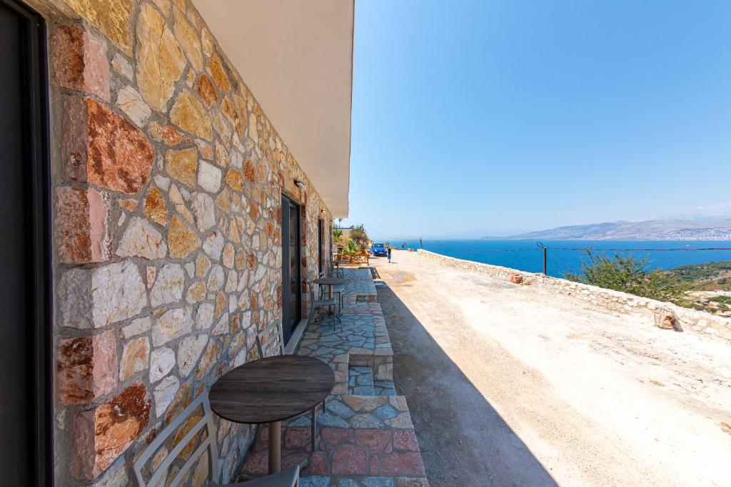 a stone wall with a table and a bench on a street at Santa Oliva Suites in Ksamil