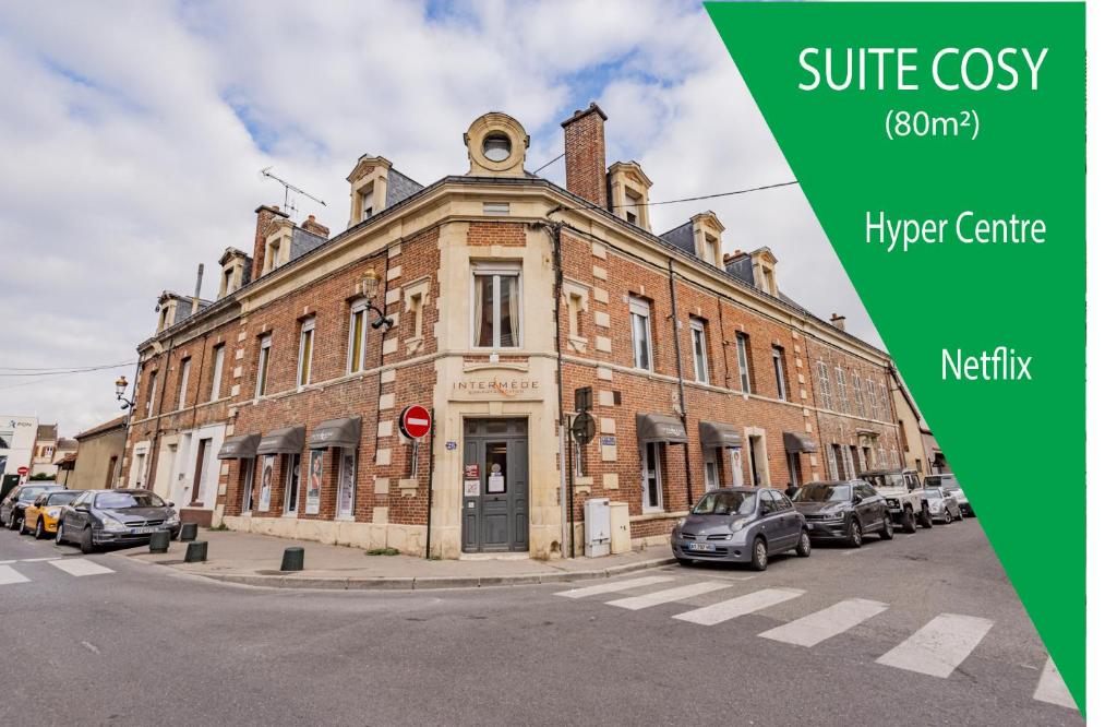 un vieux bâtiment en briques dans une rue avec des voitures garées devant dans l'établissement Suite PREMIUM LE FIGARO 1, à Épernay