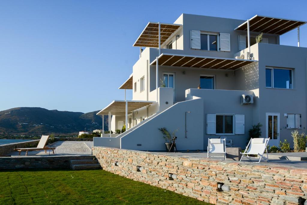 a large white house with a stone wall at Pharos Apartments in Gavrio