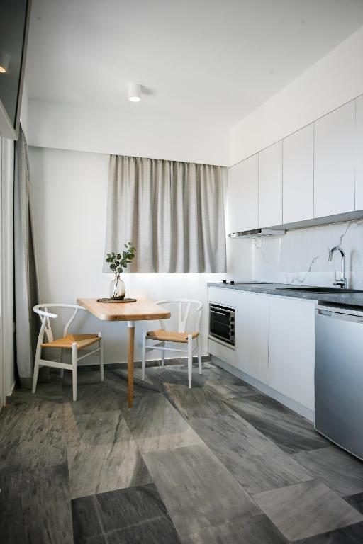 a kitchen with white cabinets and a table and chairs at Pharos Apartments in Gavrio
