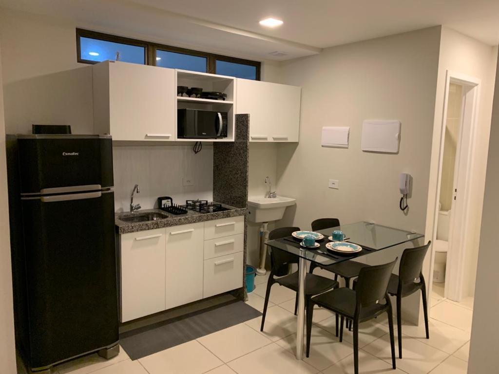 a kitchen with a black refrigerator and a table with chairs at Flats Mobiliados Zona Norte, Casa forte, recife, Aluguel por temporada Direto com o dono in Recife