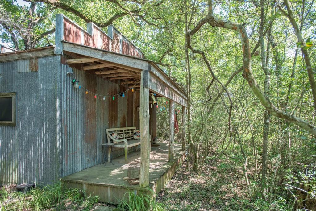 a wooden building with a porch in the woods at 7F Lodge and Events in College Station