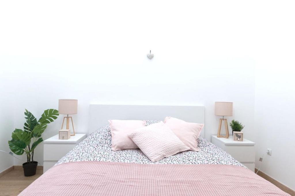 - une chambre blanche dotée d'un lit avec des draps et des oreillers roses dans l'établissement Appartement grand standing VAUBAN 10 Personnes centre historique de Colmar, à Colmar