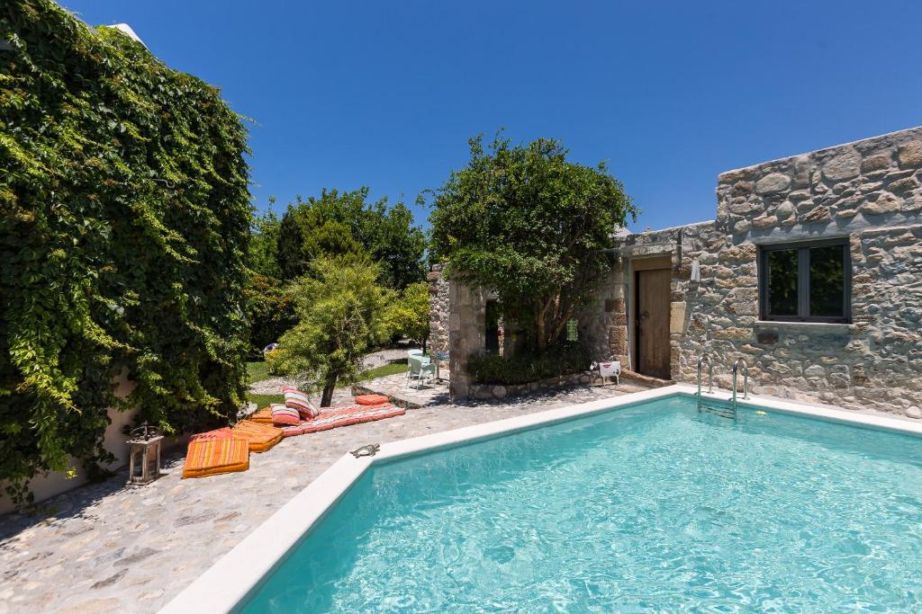 a swimming pool in front of a stone house at Muazzo Creta Stone House, a Fairytale Cottage, By ThinkVilla in Pigi