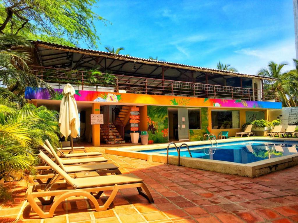 a resort with a swimming pool and lounge chairs next to it at The Cantamar Beach Hostel in Santa Marta