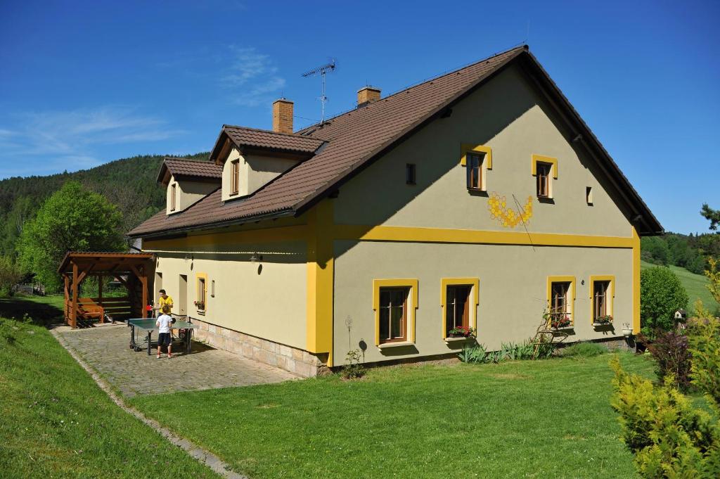 una casa amarilla y blanca con una persona parada frente a ella en Rodinné ubytování Debrné, en Hostinné