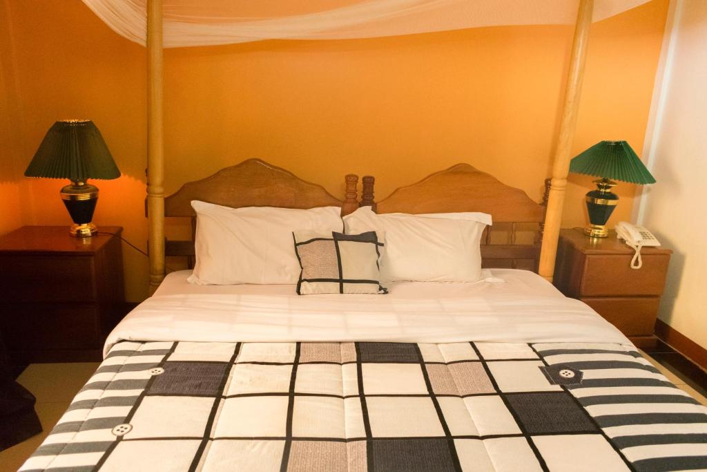 a bedroom with a large bed with two lamps at Kayegi Hotel Mbale in Mbale